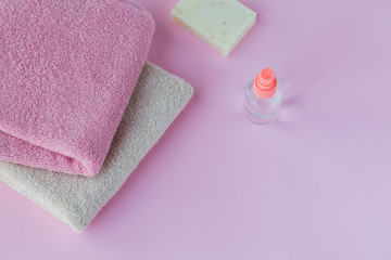 Obraz na płótnie Canvas Homemade soap, liquid antibacterial hand sanitizer and pink towels on a light pink background.