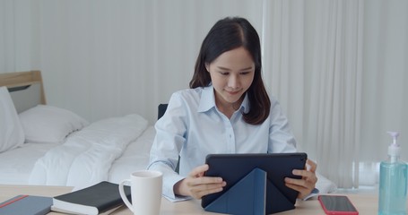 Naklejka premium Young woman work from home with tablet in bedroom