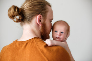 Portrait of young bearded Caucasian father hugging and kissing newborn baby.Male man parent holding child.Single dad family life concept.Studio portrait of a happy father with a baby in his arms