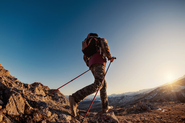 Hiker with backpack explores mountains at sunset