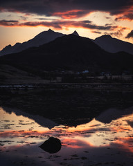 Dramatic sunset over the mountains and the sea of Lofoten islands in Norway - mountain are reflecte in the sea