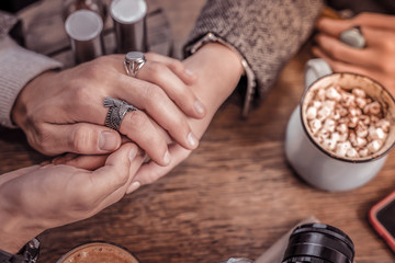 Cute photo of man and woman holding hands in cafe