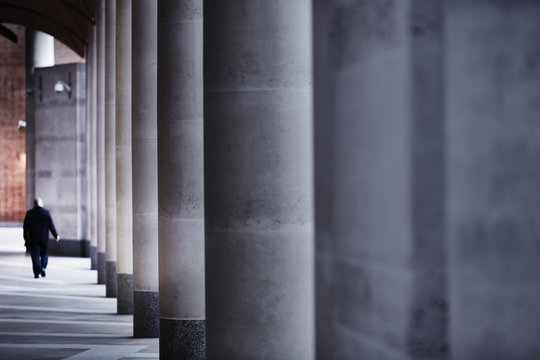 A solitary businessman walks past colonnades in the city