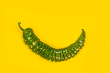 Pimiento verde italiano cortado en rodajas sobre fondo amarillo aislado. Vista superior. Copy space