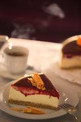 closeup of cheesecake portion with strawberry sauce and orange chocolate. Pouring hot tea. Teahouse.