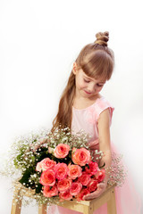 portrait of a small beautiful girl, in a pink dress, with long blond hair, looking at roses and smiling, on a white background, close-up, vertically