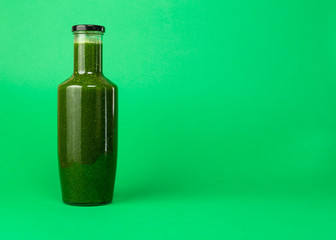 Fresh celery spinach juice in a glass bottle isolated on green background. Healthy eating Detox juice diet.