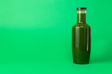 Fresh celery spinach juice in a glass bottle isolated on green background. Healthy eating Detox juice diet.