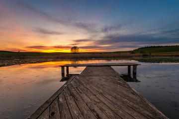 wooden jetty at a small lake during a beautiful sunset