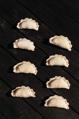 Raw dumplings on black wooden background. Natural homemade food.