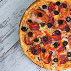 Flat lay photograph of tasty Italian pizza on grey rustic wooden background. Copy space banner.
