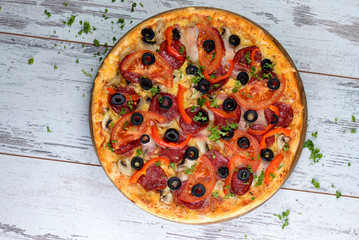 Flat lay photograph of tasty Italian pizza on grey rustic wooden background. Copy space banner.