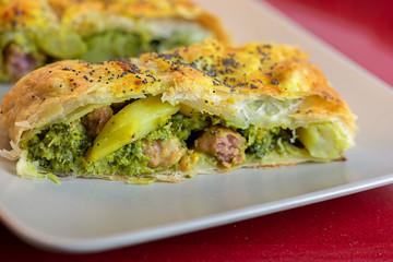 Close up of a broccoli and sausage strudel slice.
