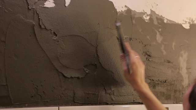 Worker putting tile glue on wall
