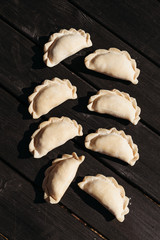 Raw dumplings on black wooden background. Natural homemade food.