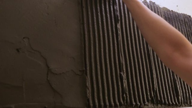 Worker putting tile glue on wall