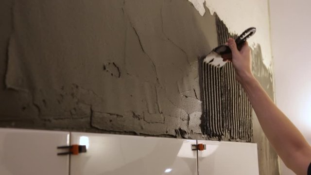 Worker putting tile glue on wall