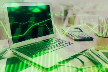 Stock market graph on background with desk and personal computer. Multi exposure. Concept of financial analysis.