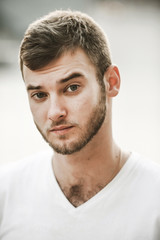 Fototapeta premium smiling friendly guy with a variety of emotions; a man in a white T-shirt and jeans with a clock on his hand;