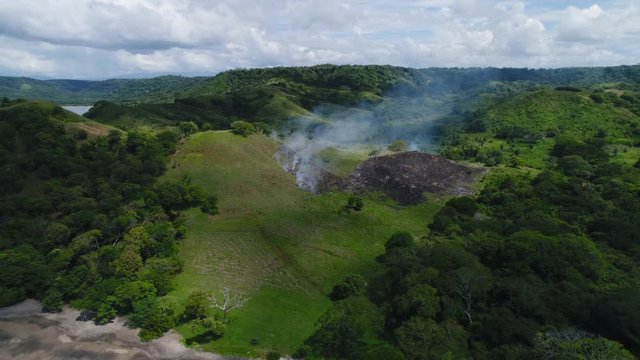 Aerial shot of small fire at the tropical coastline by Playa Arenillas in Costa Rica peninsula Papagayo coast guanacaste
