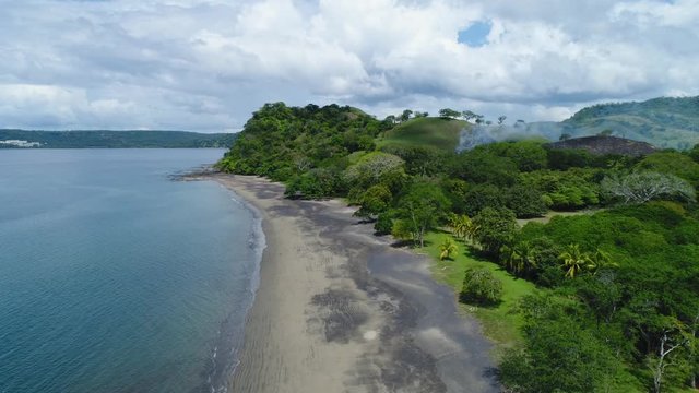 Aerial shot of small fire at the tropical coastline by Playa Arenillas in Costa Rica peninsula Papagayo coast guanacaste