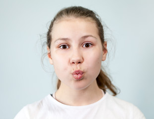 Pre-teen girl makes a kiss with lips, looking at camera, portrait on background, emotions series.