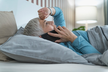 Mature Woman Lying in Bed, Talking Over the Phone