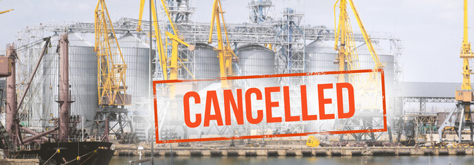 Red inscription "cancelled" on a blurred background  cranes and granaries in the port. Concept: Global economic crisis, reduction of world  trade, grain export reduction due to a pandemic