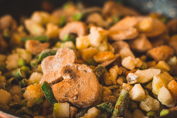 Close-up of frozen mushrooms mixed with peas, asparagus and zucchini. Mixture for healthy and balanced nutrition.