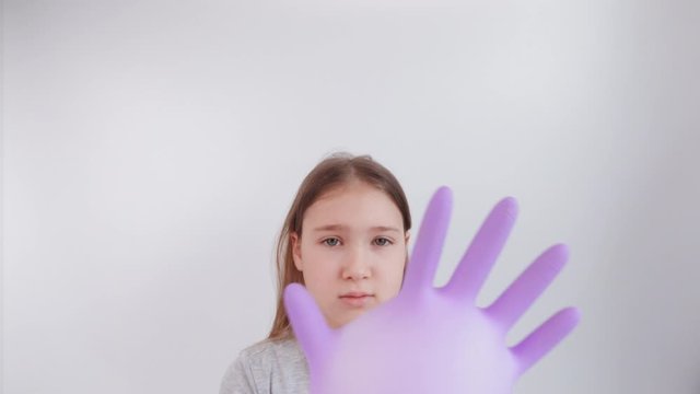 Young sad girl play with protective medical glove. Teenager with glove inflated like balloon. Quarantine, self isolation, depression, social distance, mental health concept. Stock slow motion video.