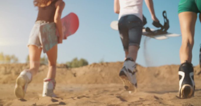 Three hipsters enjoying summer vacation. Adventure atmosphere. Young people guys with sandboard in hands running high at shining sunset. Holidays, sport, journey, travel, happiness, friendship concept