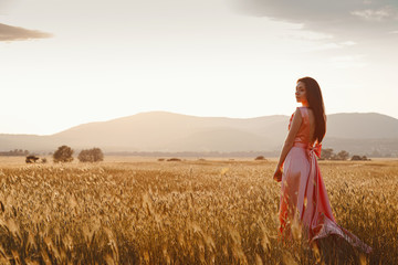 girl dancing in a field in a beautiful pink dress at sunset