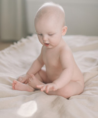 Healthy baby in bed.  Cute happy baby girl sitting and playing.  A portrait of a beautiful baby girl. Childhood, baby care concept