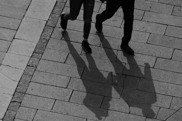 silhouette and shadow of legs of two people crossing the street