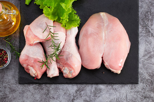 Raw chicken meat, chicken legs and spices on dark background