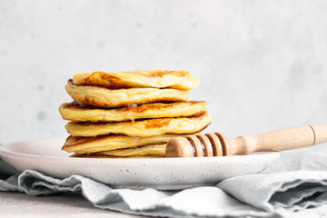 A stack homemade pancakes with honey. Light grey concrete background. Breakfast concept. 