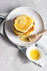 A stack homemade pancakes with honey. Light grey concrete background. Breakfast concept. 