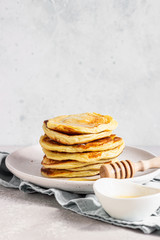A stack homemade pancakes with honey. Light grey concrete background. Breakfast concept. 