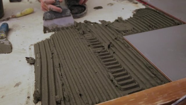 Worker putting tile glue on floor