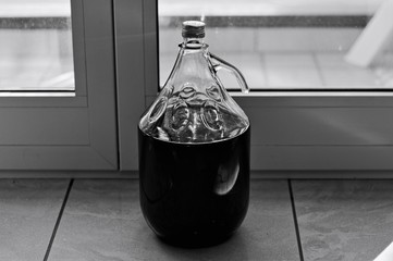 A big glass bottle of red wine on the floor (Pesaro, Italy, Europe)