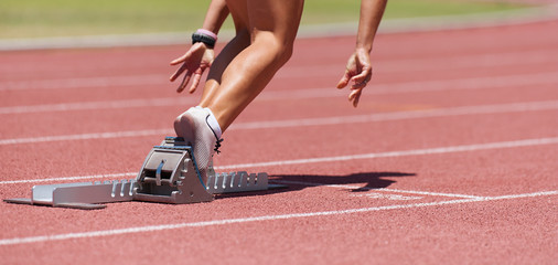 Athlete female feet on starting block ready for a sprint start