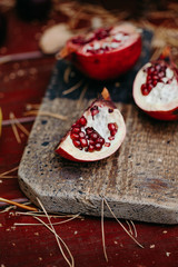 Pomegranate fruit on the wooden cut board. Outdoor table
