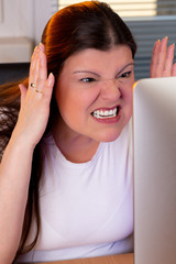 Closeup of a professional woman working at home. She is angry while looking at the computer screen.