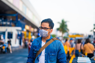 Concept, diseases, viruses, allergies, air pollution. Portrait of young man wearing a protective mask, walking in the city.The image face of a young man wearing a mask to prevent germs, toxic fumes...