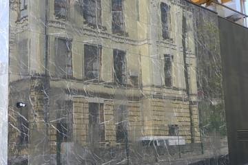reflection of yellow old building in the smooth glossy polished marble wall of new modern house