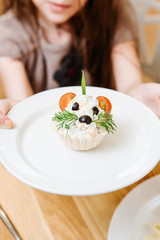 Plate with fun children salad looking like mouse in the little girl's hands