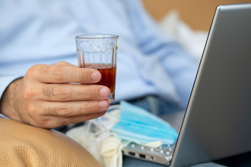 man seating in sofa with glass of wine, medical mask, notebook