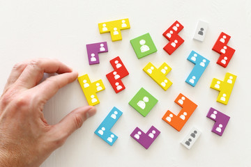 business concept image of tangram puzzle blocks with people icons over wooden table ,human resources and management concept