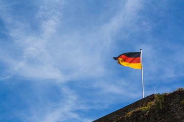 A German flag flying in the wind and nailed to a stone wall.