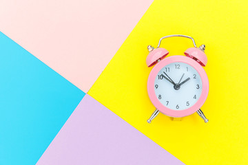 Ringing twin bell classic alarm clock isolated on blue yellow pink pastel colorful geometric background. Rest hours time of life good morning night wake up awake concept. Flat lay top view copy space.